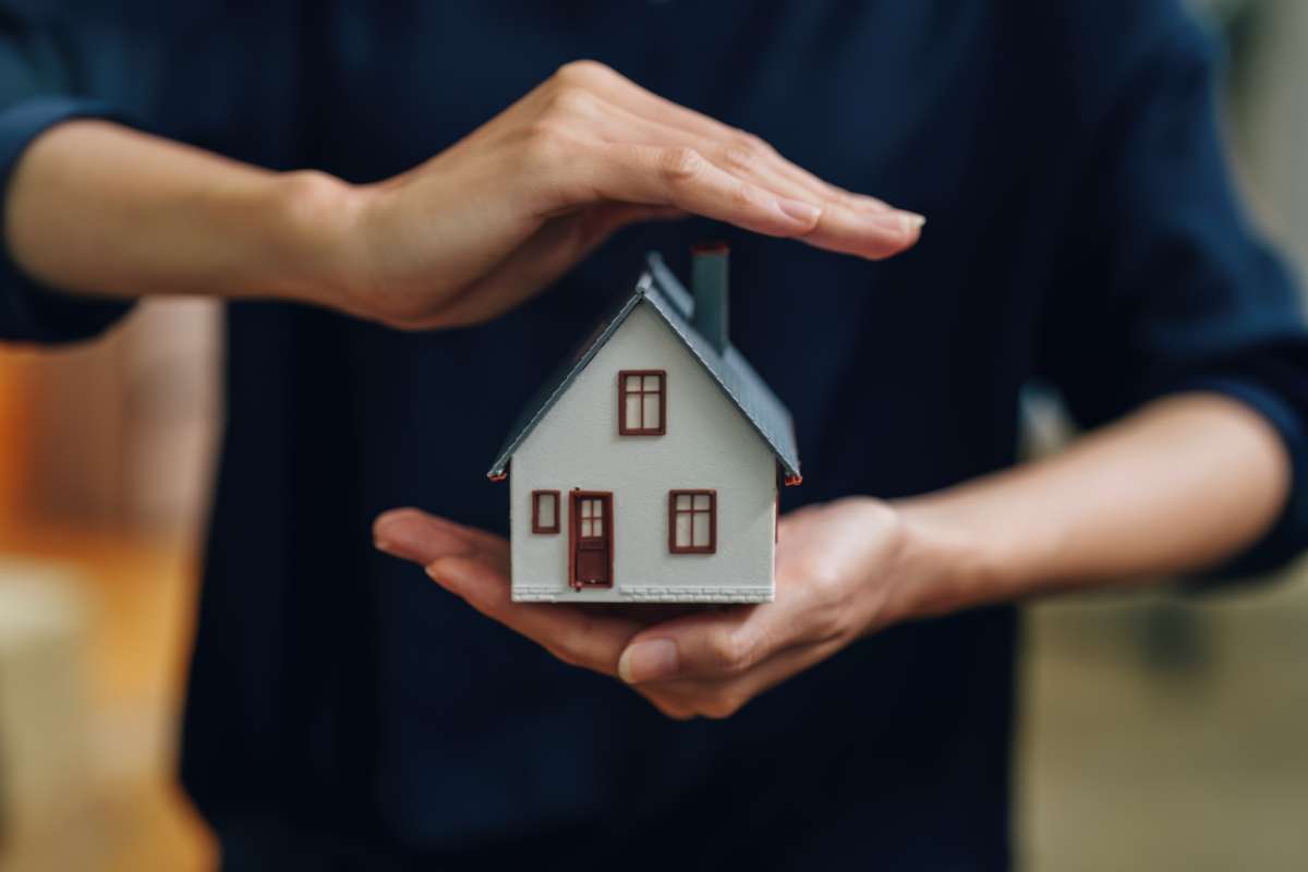 Femme tenant dans ses mains une petite maison à vendre